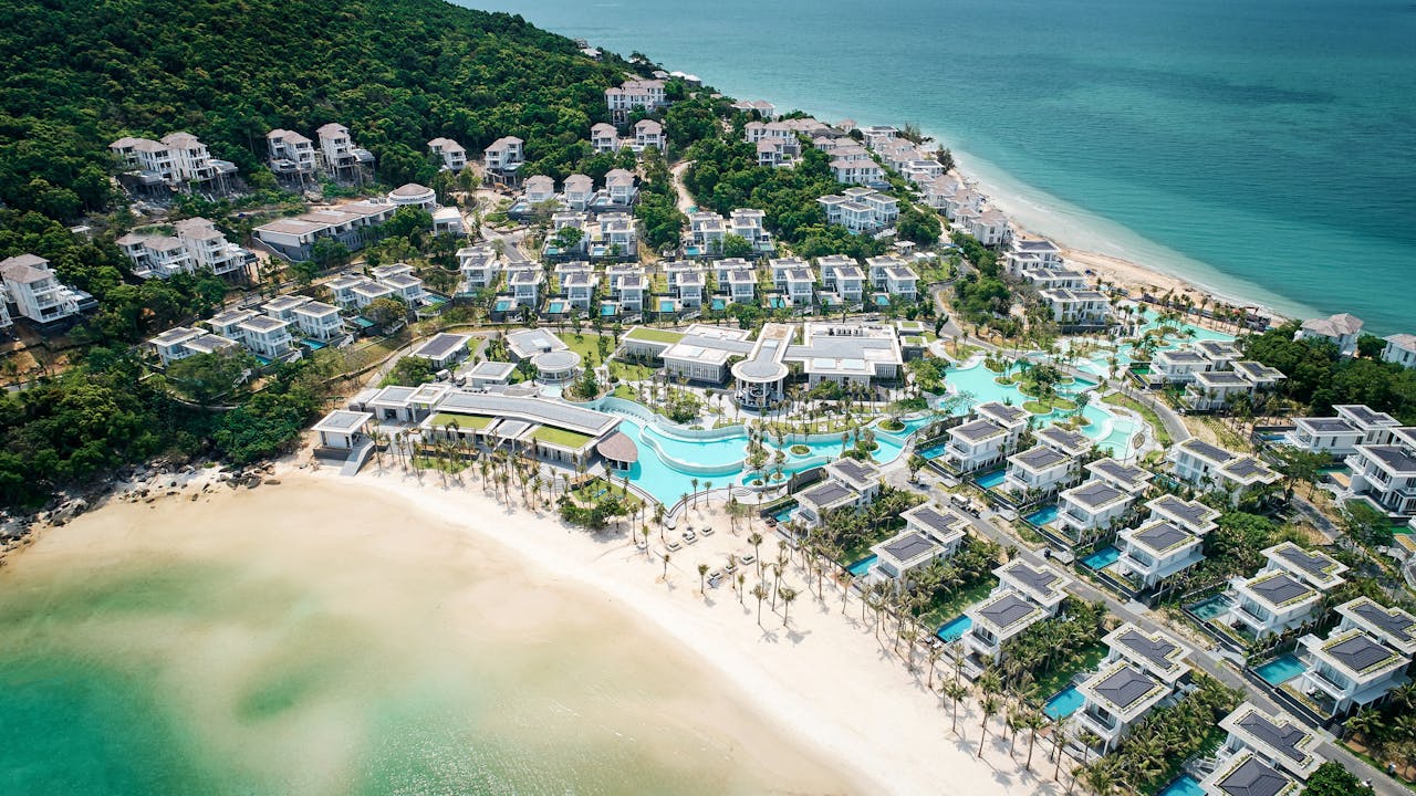 Stunning aerial view of a luxurious beach resort with villas and pools on tropical coastline in Vietnam.